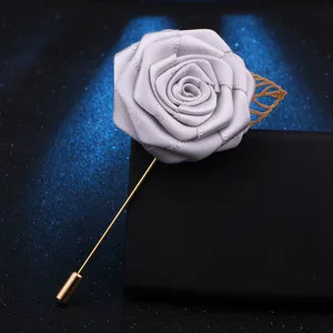 Detailaufnahme einer silbernen Stoffrosenbroche mit goldenem Stiel und dekorativem Blatt.