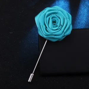 Gros plan détail d'une broche rose en tissu turquoise vif avec une longue tige métallique.