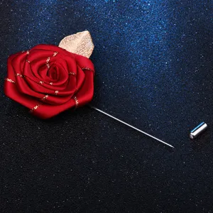 Broche rose en tissu rouge avec feuille dorée et longue épingle pour costume homme.