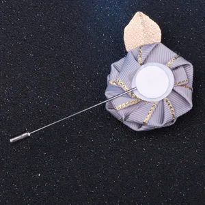 Handmade fabric ribbon rose brooch detail, gold leaf accessory, lapel pin close-up display.