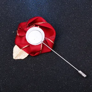 Gros plan détail de la broche rose en tissu rouge avec feuille dorée et longue épingle.