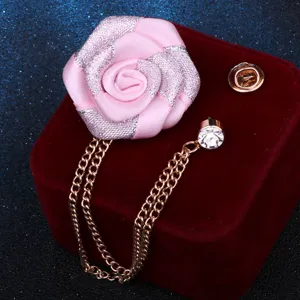 Vue de détail de l'élégante broche fleur en tissu rose avec chaîne à franges et strass.
