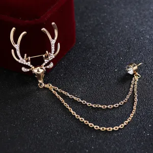 Gros plan sur la broche tête de cerf dorée avec strass et chaînes doubles délicates.
