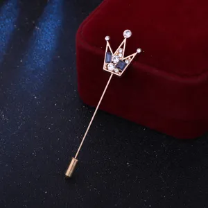 Dettaglio della spilla a corona con cristalli brillanti e pietre blu per abiti eleganti.