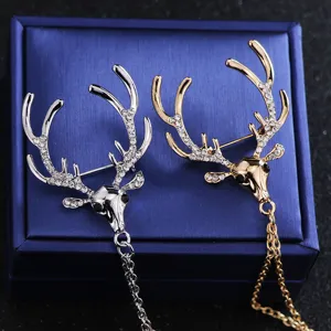 Gros plan détaillé de la broche cerf tendance ornée de strass brillants et d'une fine chaîne à pampilles.