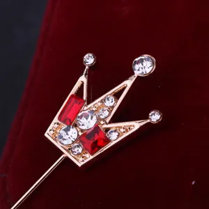 Dettaglio spilla a corona di cristallo mini, elegante gioiello dorato da uomo.