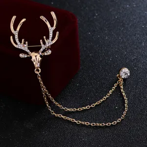 Gros plan exquis de broche cerf en cristal avec chaînes à pampilles dorées doubles.