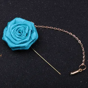 Vue rapprochée détaillée d'une broche boutonnière de rose en tissu bleu avec chaîne dorée.