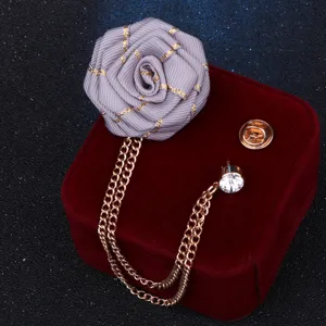 Nahaufnahme einer handgefertigten Stoffrosen-Anstecknadel mit Kette und Strass.