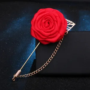 Gros plan détaillé de la broche fleur de rose en tissu rouge avec épingle et chaîne dorées.