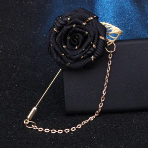 Detailaufnahme der schwarzen Schleifen-Rosenbrosche mit goldener Kette auf dunklem Grund.