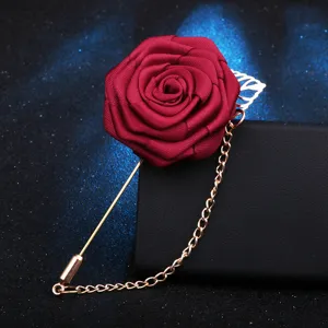 Vue détaillée d'une broche rose en tissu bordeaux élégante avec longue chaîne dorée.