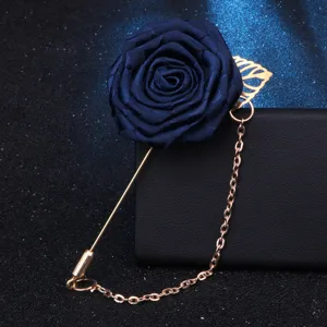 Vue détaillée de la broche rose en tissu bleu marine avec chaîne dorée et feuille pour costume.