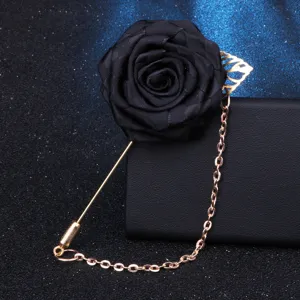Broche fleur en tissu noir avec longue épingle dorée, détail d'accessoire de costume.