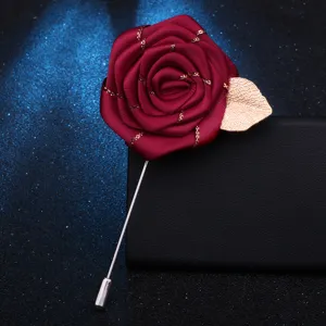 Vue détaillée de la broche rose bourgogne avec feuille dorée, élégant boutonnière en tissu.