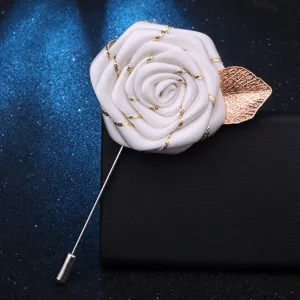 Vue détaillée de la boutonnière rose en tissu blanc avec feuille dorée et longue épingle.