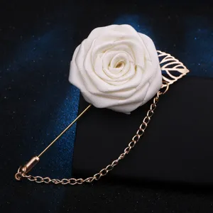 Gros plan détaillé d'une broche rose en tissu blanc avec épingle et chaîne dorées.