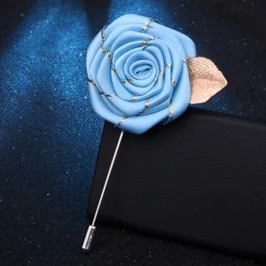 Élégante épingle de revers rose en tissu bleu avec feuille d'or pour les costumes hommes.