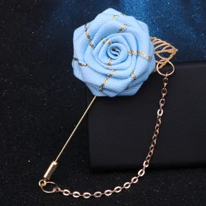 Nahaufnahme Detail der eleganten blauen Bandrosen-Brosche mit schicker goldener Kette.