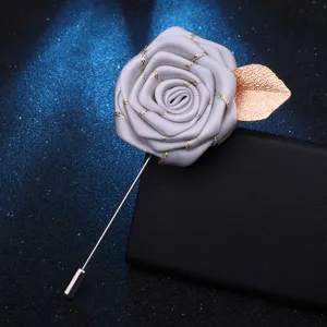 Gros plan d'une épingle à revers rose en tissu gris avec feuille dorée et longue épingle.