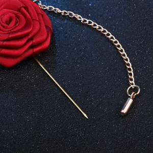 Broche rose en tissu rouge avec chaine dosee, accessoire elegant pour costume homme, raffine.
