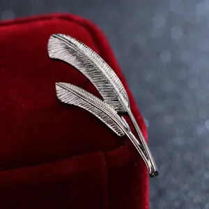 Close-up detail of vintage silver double feather brooch pin, exquisite metallic texture accessory.