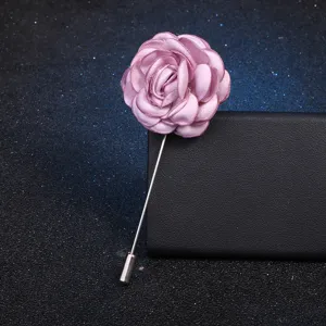 Vue détaillée de l'élégante épingle de revers en tissu rose camélia avec longue tige.