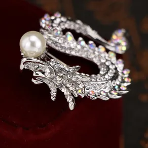 Detailed close-up of a sparkling dragon brooch with rhinestone crystals and a elegant pearl.