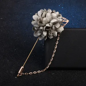 Gros plan détaillé d'une élégante broche fleur en tissu gris avec chaîne dorée fine.