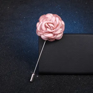 Élégante broche fleur en tissu rose avec longue épingle en métal, design floral délicat.