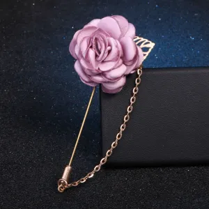 Fabric flower brooch detail featuring pink rose petal design with gold chain pin aesthetic.
