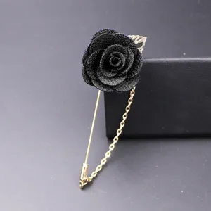 Nahaufnahme des eleganten schwarzen Stoff-Rosen-Reverssteckers mit langer goldener Kette.
