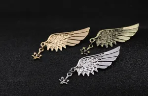 Primer plano del broche metálico de ala de ángel con colgante y textura de plumas.