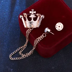 Nahaufnahme einer goldenen Kronen-Brosche mit hängenden Ketten und funkelnden Strasssteinen.