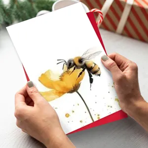 Gros plan d'une carte de vœux aquarelle abeille et fleur avec enveloppe rouge, thème nature.