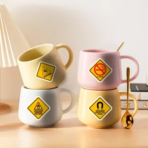 Creative ceramic mug set with warning sign prints and golden spoons, stylish coffee cups.