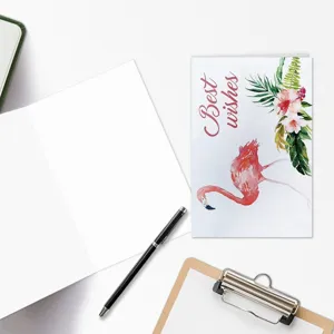 Watercolor flamingo greeting card detail view with envelope and pen on white desk background.