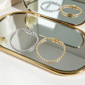 Dettaglio ravvicinato di eleganti bracciali in zircone placcati oro e argento su uno specchio