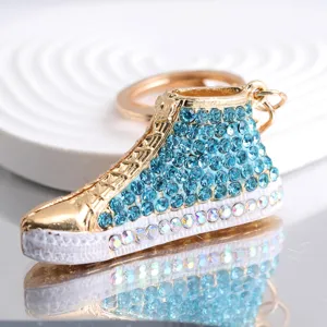 Nahaufnahme eines glitzernden hellblauen Strass-Sneaker-Schlüsselanhängers auf Reflexion