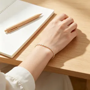 Dettaglio di un bracciale placcato oro con zirconi a baguette indossato al polso.