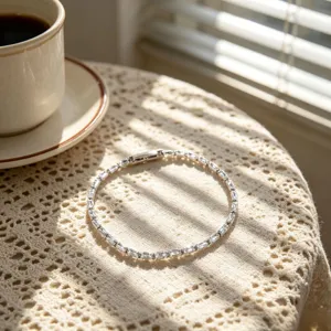 Primo piano del bracciale con zirconi su tovaglia di pizzo con ombre solari.