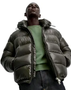 Low-angle view of a model wearing a shiny olive green winter hooded puffer jacket coat
