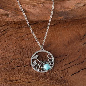 Vintage silver alloy necklace detail showing circular pendant with turquoise stone and leaves.