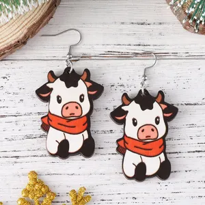 Gros plan de boucles d'oreilles en bois de vaches mignonnes avec écharpe rouge, détail fête.