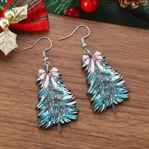 Gros plan sur des boucles d'oreilles en bois en forme de sapin avec nœud et texte de fête.