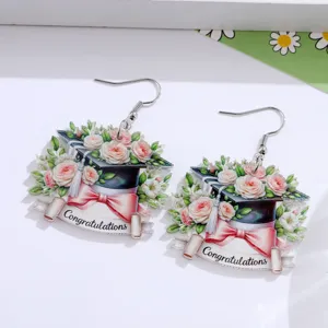 Detailansicht von Abschlusskappe Acryl Ohrringe mit rosa Rosen, Schleife und Spruchband.