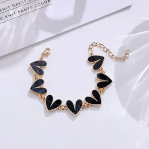Nahaufnahme Detail eines modischen goldfarbenen Kettenarmbands mit schicken schwarzen Herzen.