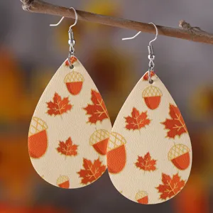 Nahaufnahme von Tropfen-Kunstleder-Ohrringen mit Herbst-Ahornblättern und Eicheln.
