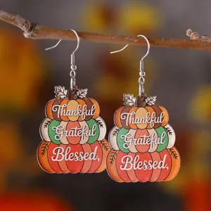 Detalle en primer plano de pendientes colgantes de acrílico de calabaza de Acción de Gracias.