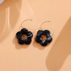 Nahaufnahme von schwarzen Acryl Blumen Ohrringen mit goldenen Reifchen, süßer Modeschmuck.